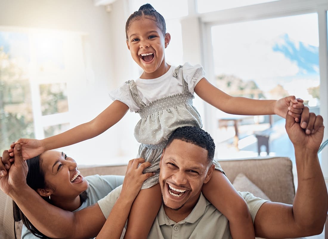 Personal Insurance - Portrait of Cheerful Young Parents Having Fun Playing with Their Daughter at Home