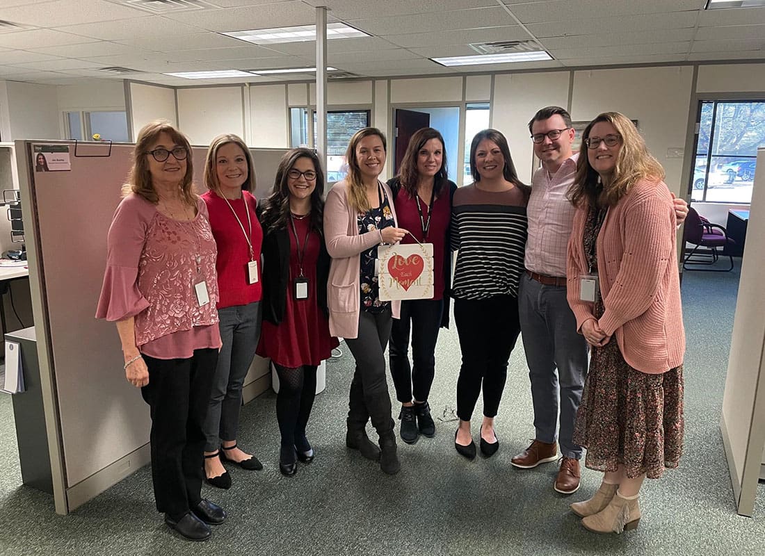 York, PA - Smiling McConkey Employees Standing Inside the Office in York Pennsylvania with One Female Employee Holding a Heart Wall Sign