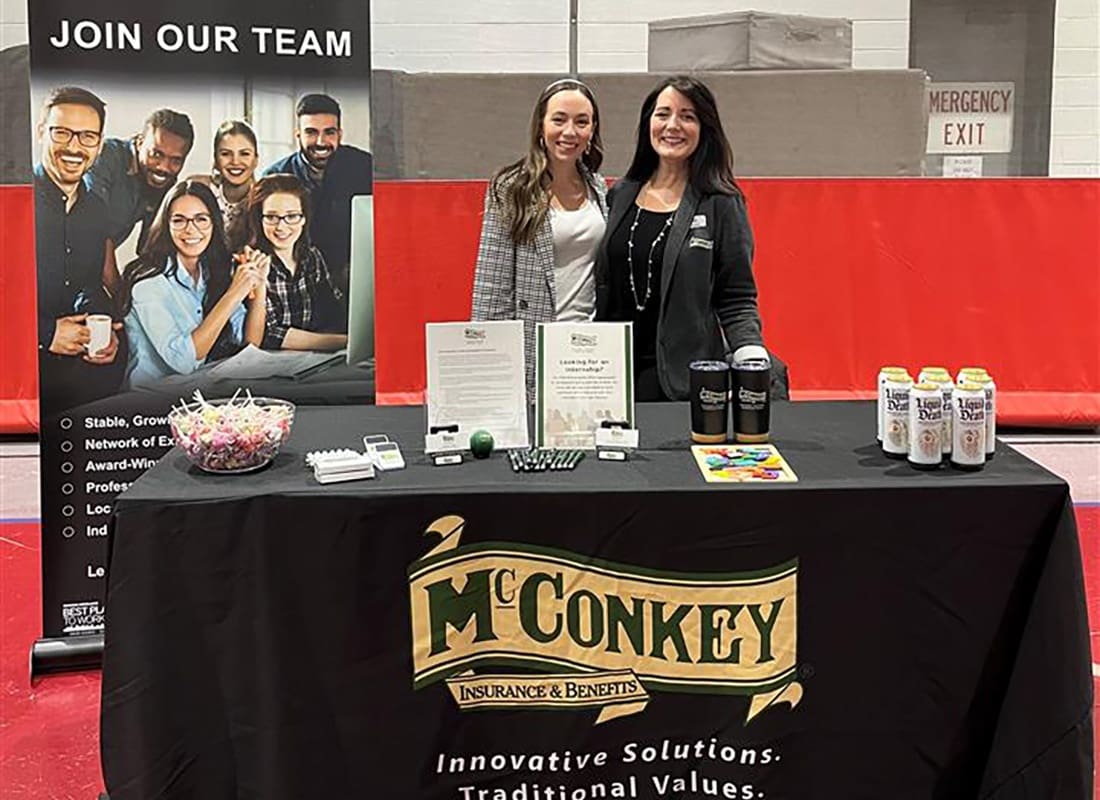 Careers - Two Smiling Female McConkey Employees Standing Behind a McConkey Employment Booth at a Career Faire
