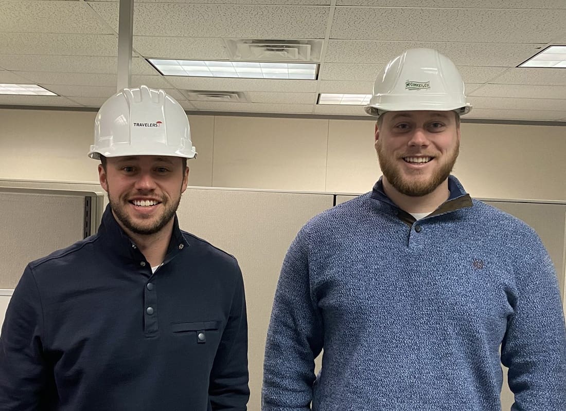 Helpful Links - Portrait of Two Smiling Male McConkey Employees Wearing White Hard Hats with Logos While Standing in the Office