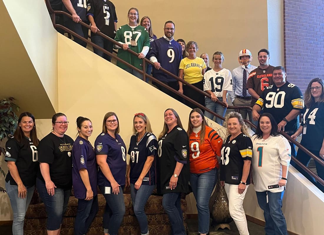 Blog - View of McConkey Team Members Wearing Sports Jerseys Standing on Next to and On the Stairs Inside the Office