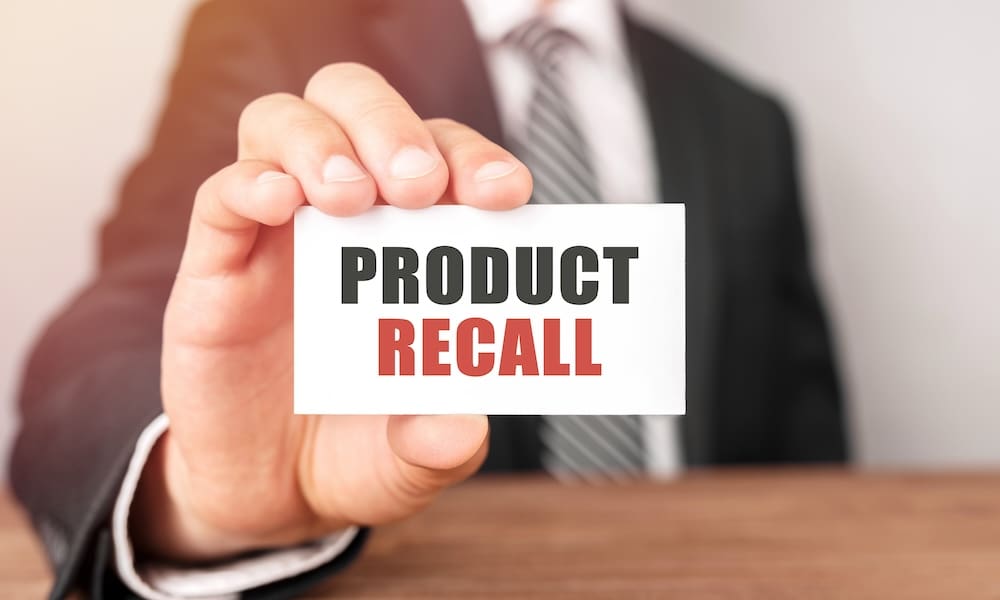 Product Recall - A Man In A Suit Holding A Card To The Camera Stating 'Product Recall'