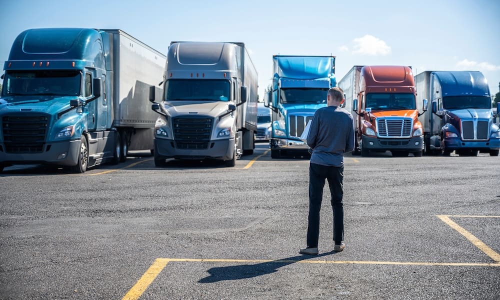 Protecting Your Fleet And You Drivers - A Driver Standing In Front Of A Fleet Of Trucks