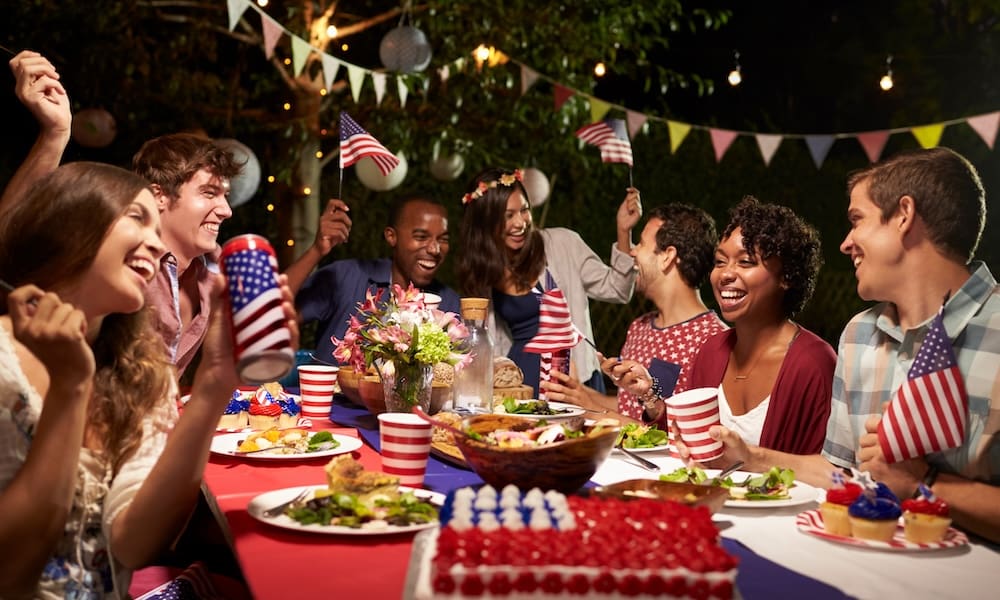 Safeguarding Your Independence/ Personal Insurance Tips for a Worry-Free Fourth of July Weekend - Family and Friends Celebrating the 4th of July Around a Table Outside