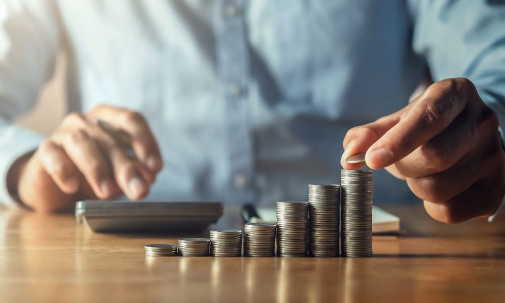 The Cost-Saving Power of Specialty Pharmacies/ A Closer Look at Prescription Affordability - Man at a desk with a calculator counting stacks of coins