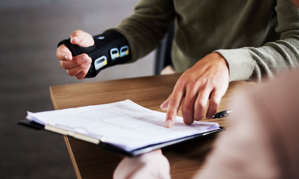 A Smarter Workers’ Comp Solution for Staffing Firms - Injured worker sitting at a desk going over a form