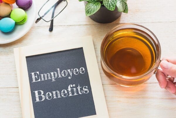 Concept Employee Benefits message on wood boards. Macaroons and glass Tea on table. Vintage tone.